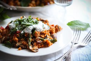 Gemüse-Couscous mit Zitronen-Minz-Joghurt auf einem Teller. Schnelles, veganes Couscous-Gericht