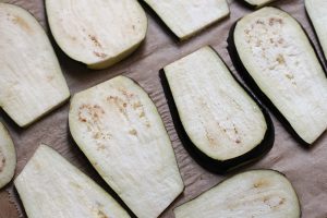 Auberginenscheiben mit Salz bestreut auf einem Holzbrett