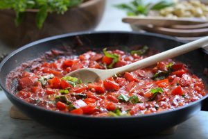 Frisch zubereitete Tomatensoße - Nahaufnahme in einer Pfanne mit vielen frischen Kräutern