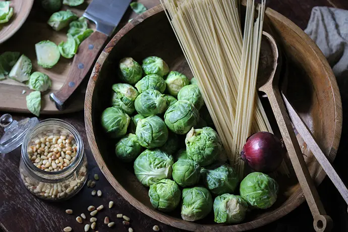Frischer Rosenkohl in einer Holzschüssel mit Hartweizennudeln und Zwiebeln
