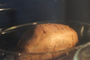 Ganze Süßkartoffel in einer Auflaufform im Ofen