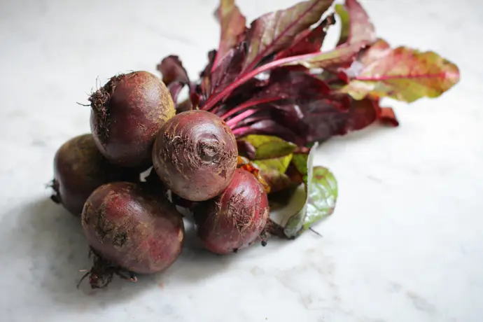 Frische Rote Bete mit Blattwerk auf einem weißen Marmortisch