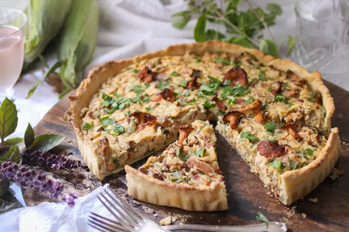 Vegane Pfifferling-Quiche, angeschnitten auf einem Tisch