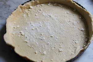 Quiche-Teigboden mit einer gabel mehrfach einpiecksen und mit Semmelbrösel bestreuen.