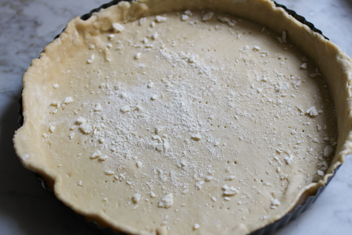 Quiche-Teigboden mit einer gabel mehrfach einpiecksen und mit Semmelbrösel bestreuen.