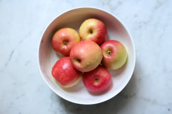 Frische Äpfel, leuchtend rot in einer weißen Schale