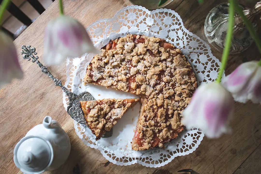 Veganer Rhabarber-Streuselkuchen angeschnitten auf einem Tisch
