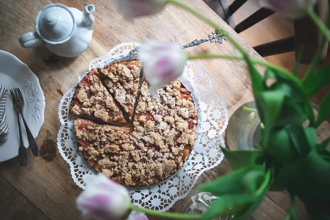 Veganer Rhabarberkuchen mit Streusel auf einem Holztisch