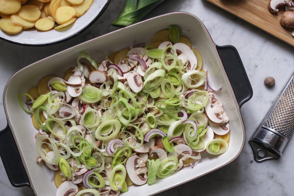 Veganes Kartoffel-Gratin mit champignons und Lauch einschichten