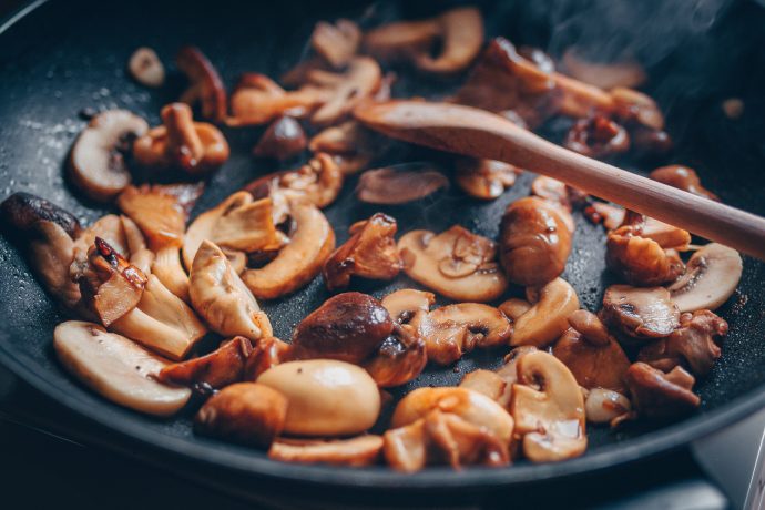 Shiitake, Steinchampignons und Austernpilze werden in einer Pfanne angebraten