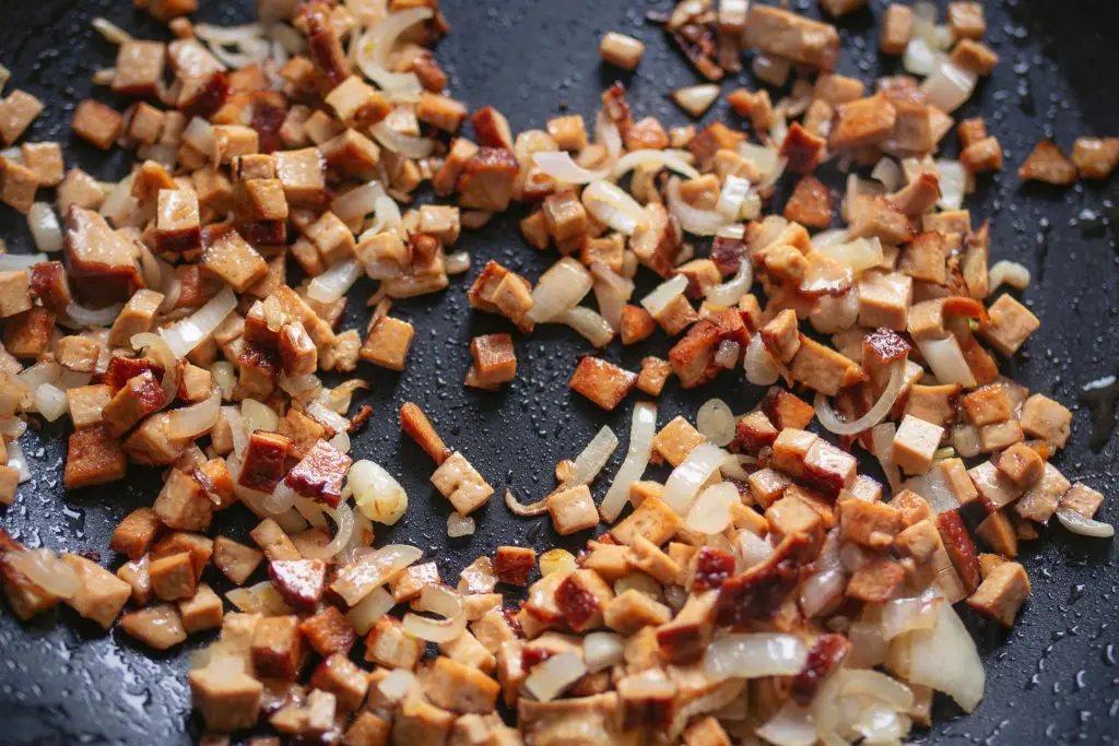 Tofu- und Zwiebelwürfel angebraten in einer Pfanne