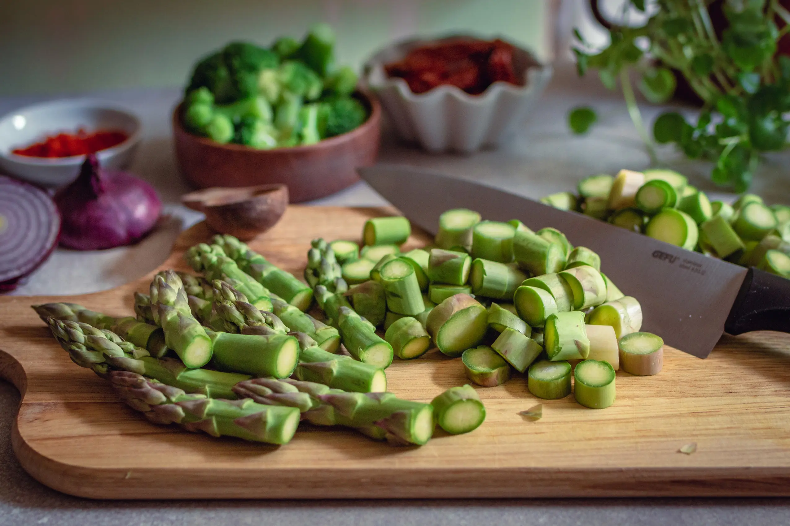 Grüner Spargel aufgeschnitten auf einem Holzbrett, vegane Spargel-Rezepte