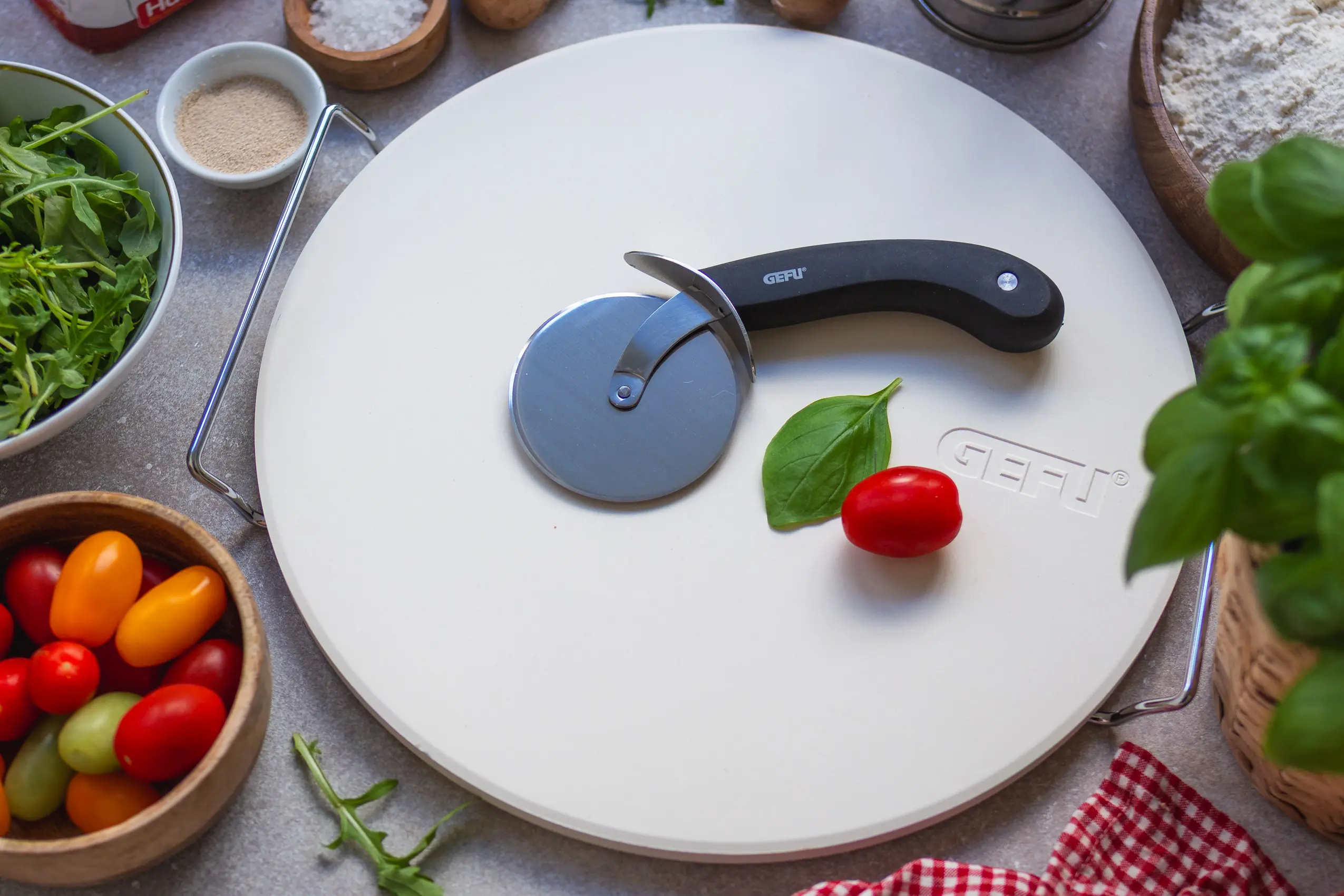 Pizzastein DARIOSO von GEFU mit Pizzarad auf einer Arbeitsfläche