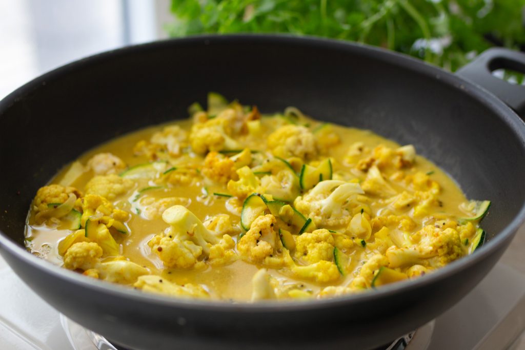 Zutaten für das vegane Madras-Curry köcheln in einem Wok