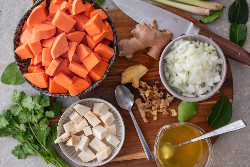 Zutaten für die vegane Süßkartoffel-Kokossuppe geschnitten und vorbereitet auf einem Brett