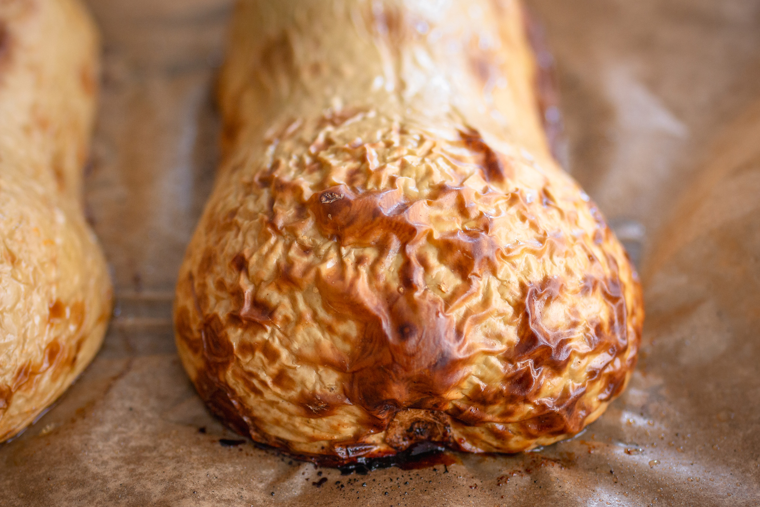 Ein halbierter, gerösteter Butternut-Kürbis auf einem Backblech