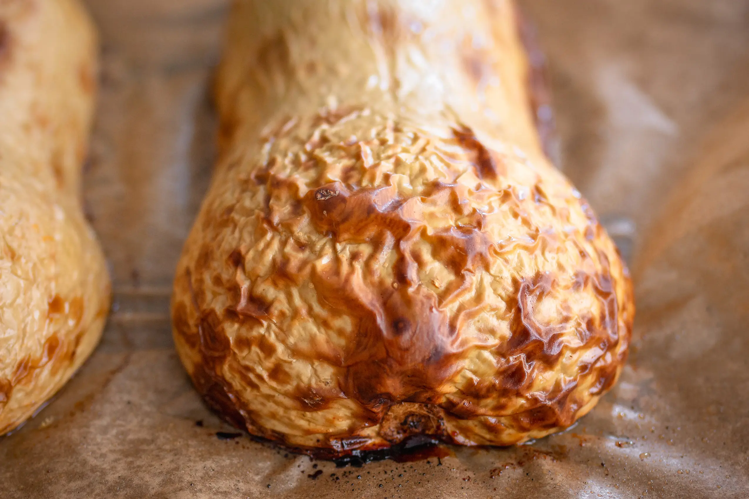 Ein halbierter, gerösteter Butternut-Kürbis auf einem Backblech