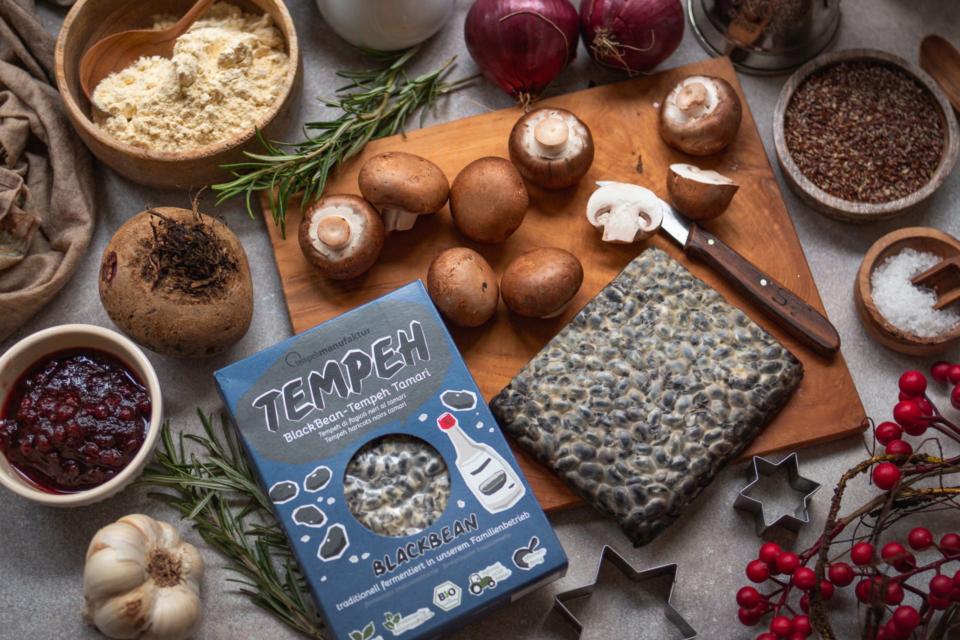 Zutaten für einen veganen Weihnachtsbraten mit Tempeh auf einem Tisch ausgebreitet.