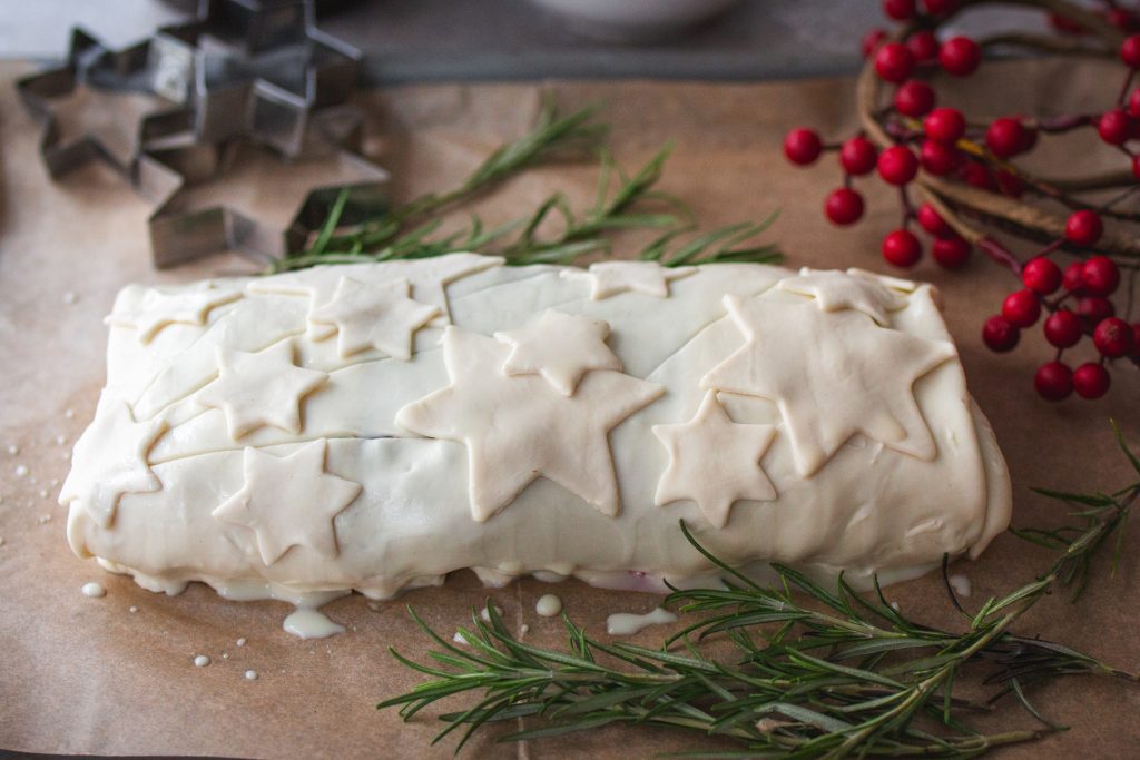 Mit Blätterteig umhüllter veganer Tempeh-Braten auf einem Blech kurz vor dem Backen