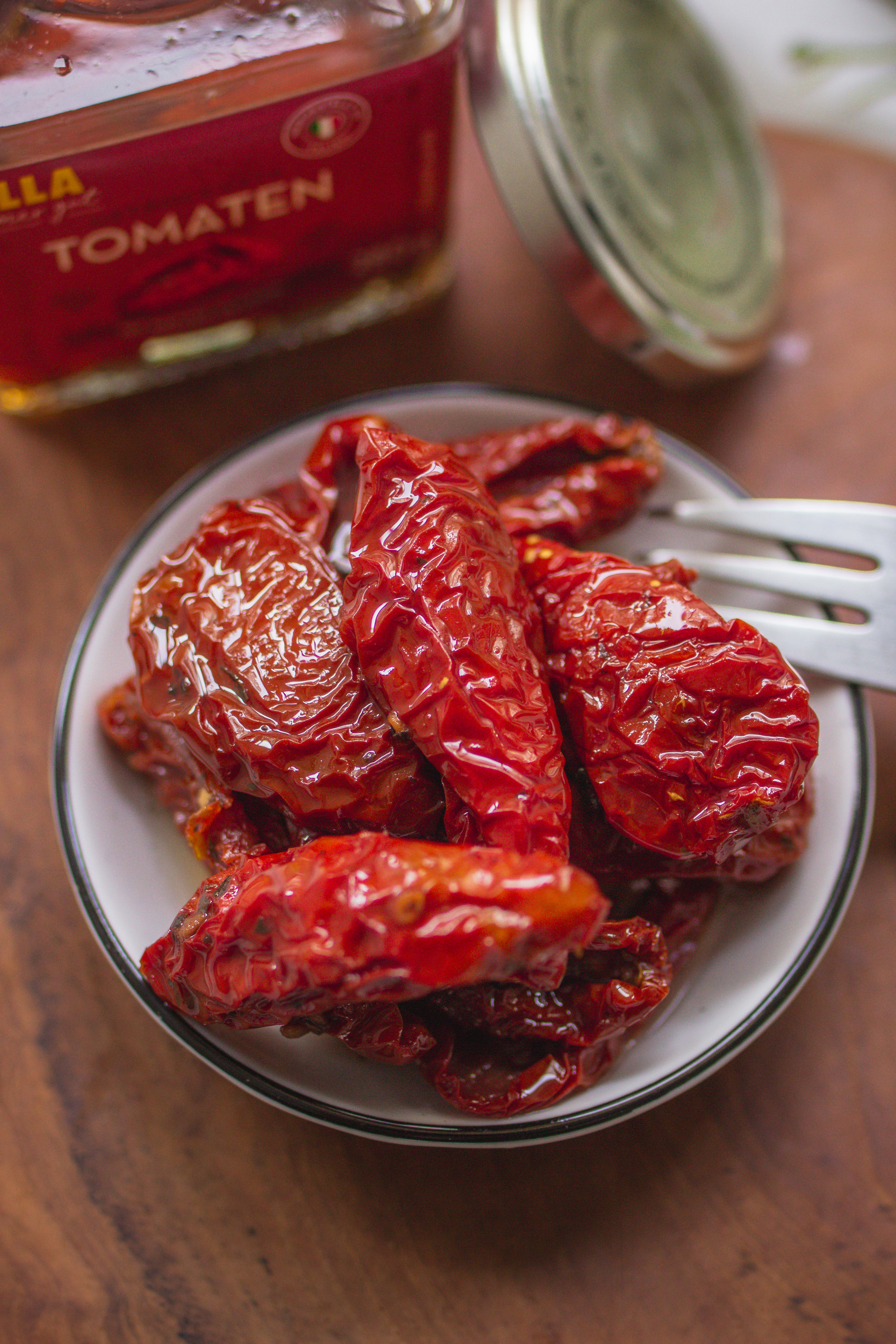 Getrocknete, in öl eingelegte Tomaten in einem Glas und einer kleinen Schale
