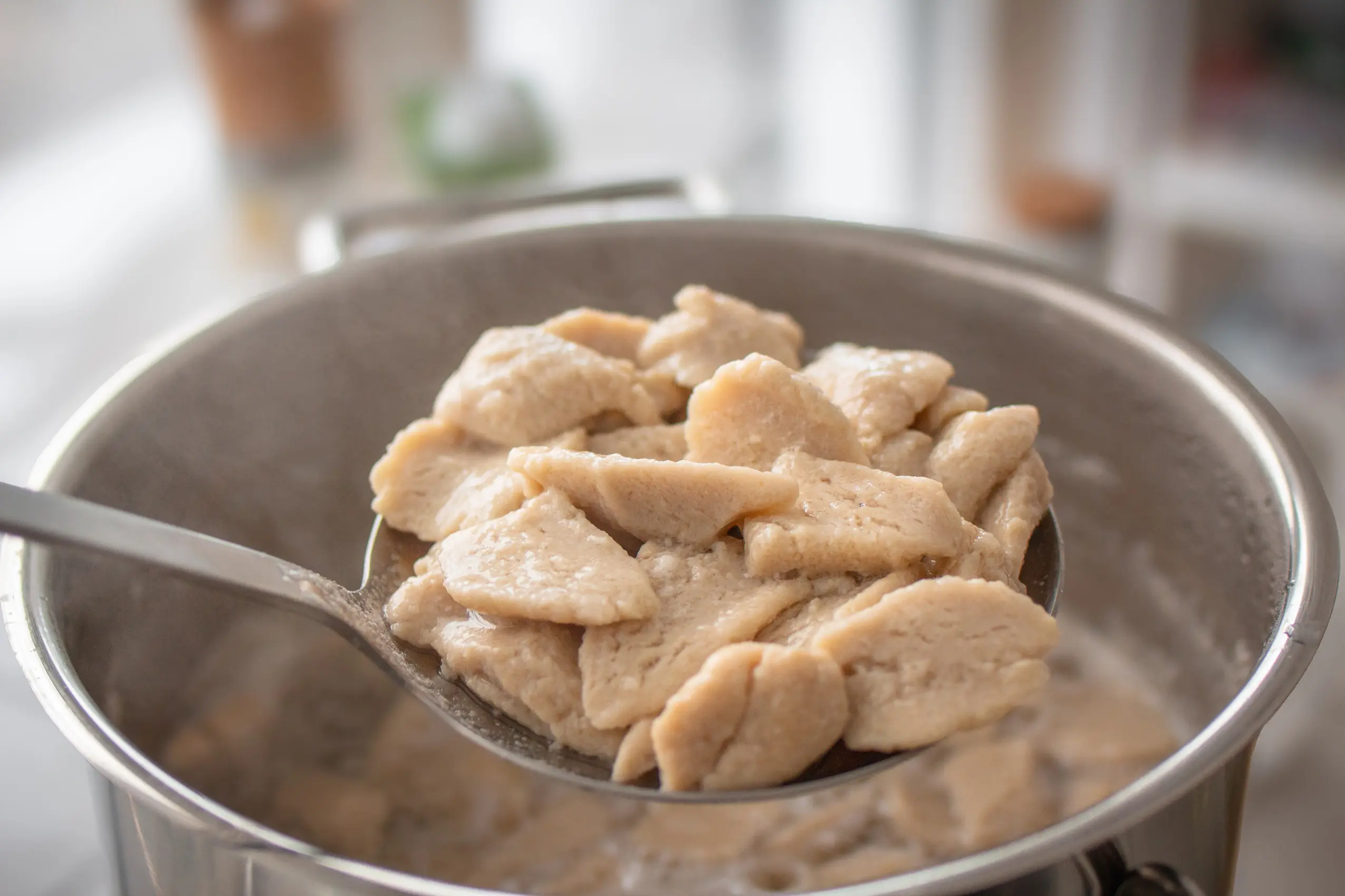 Tofu-pasta auf einem Schöpflöffel über heißem Wasser