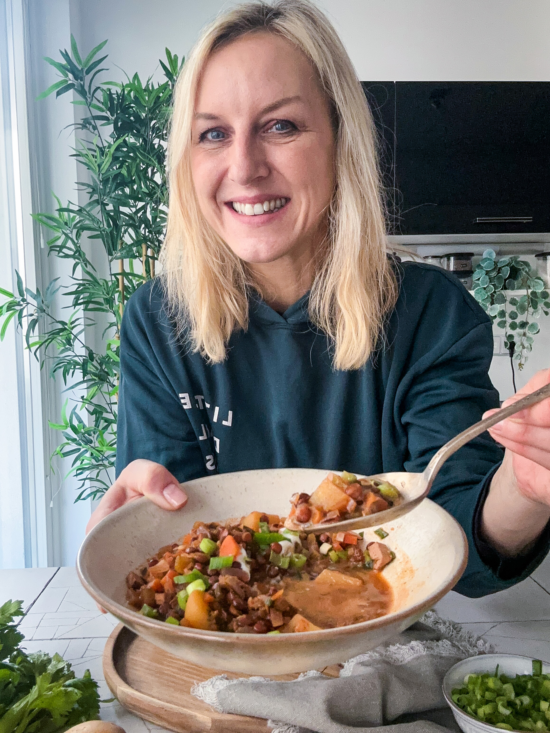 Kochbuchautorin und vegane Foodbloggerin Lea Green mit einem Teller Linseneintopf in einer Küche