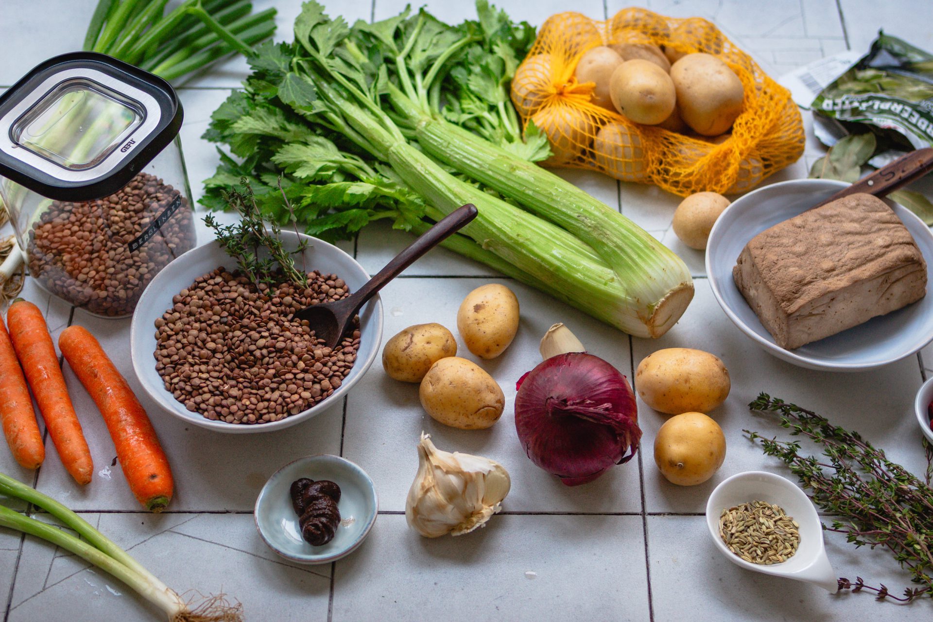 Zutaten für einen veganen Berglinseneintopf auf einer hellen Küchenarbeitsfläche