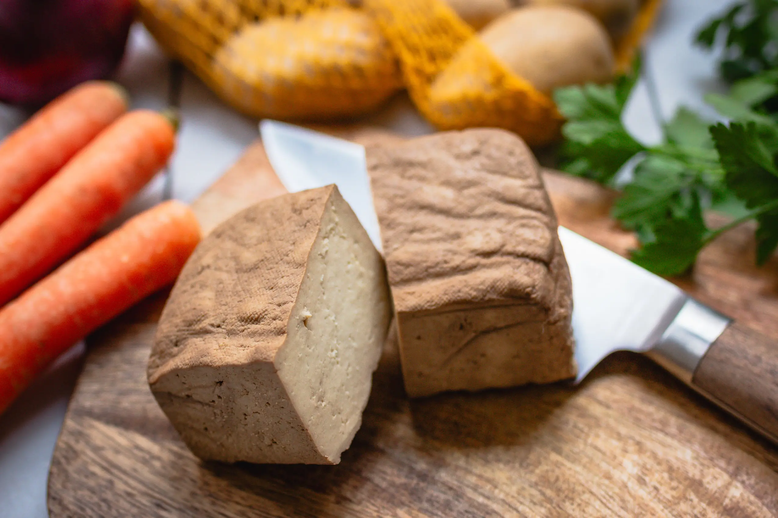 Nahaufnahme Räuchertofu halbiert auf einem Küchenbrettchen
