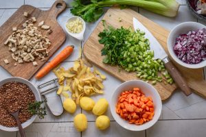 Zutaten für einen veganen Berglinseneintopf geschnitten und vorbereitet auf einer hellen Küchenoberfläche