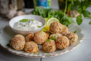 Vegane Blumenkohl-Quark-Arancini auf einem Teller mit Dip