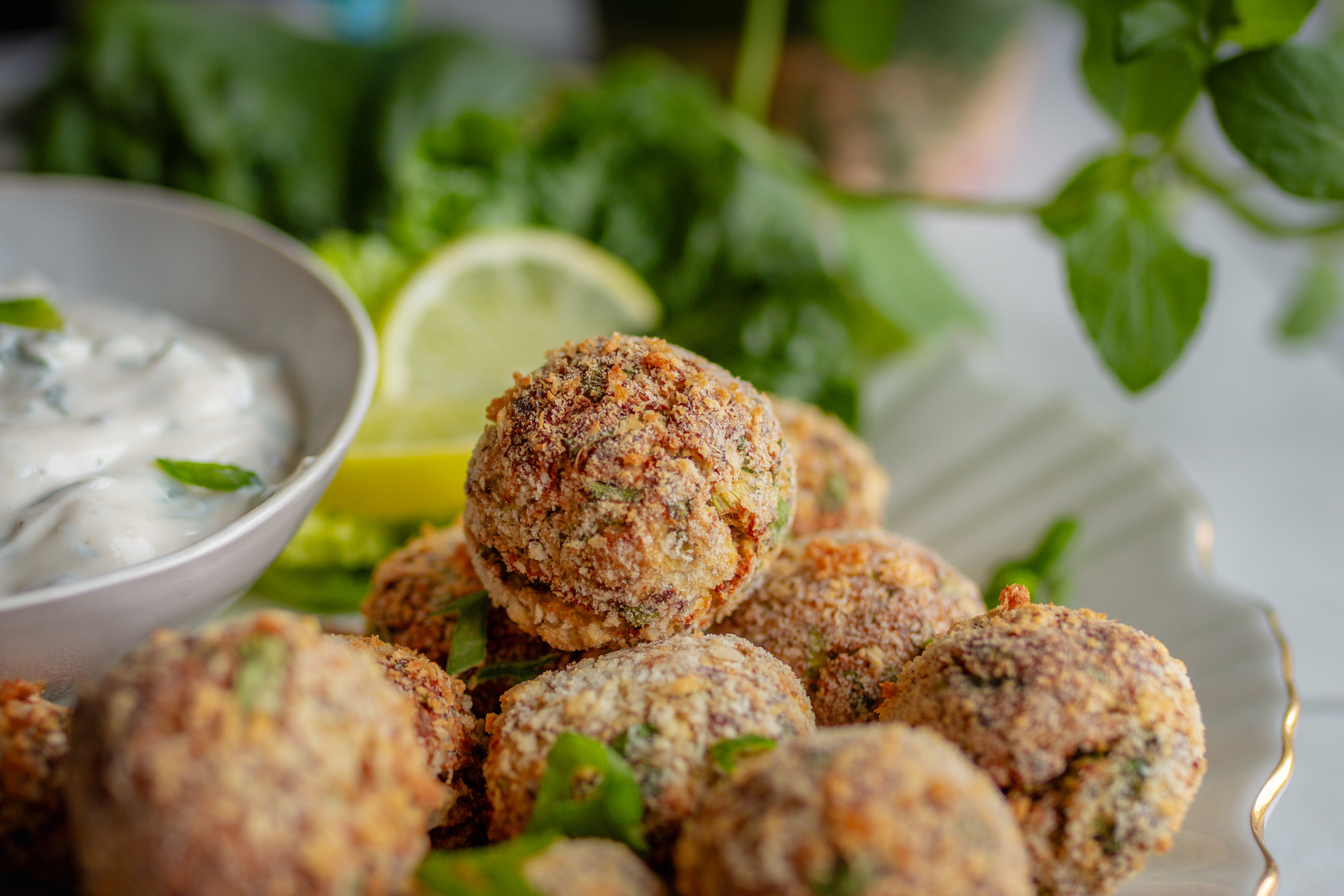 Vegane Blumenkohl-Quark-Arancini auf einem Teller mit Dip