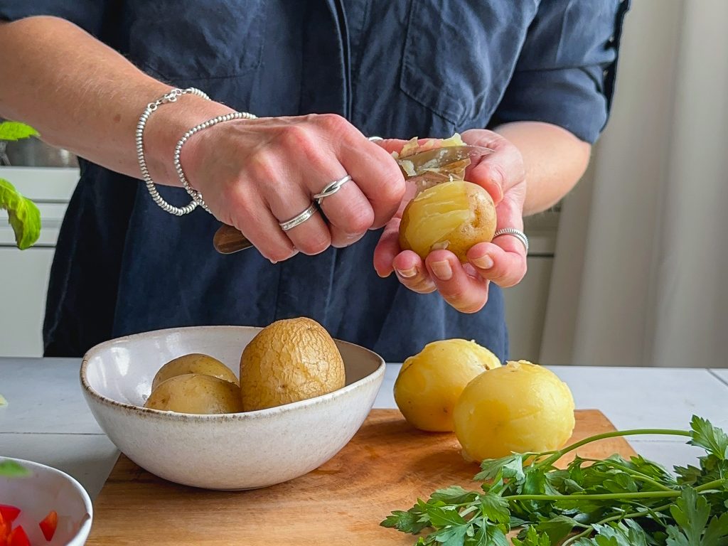 Gekochte Kartoffeln werden mit einem Messer gepellt