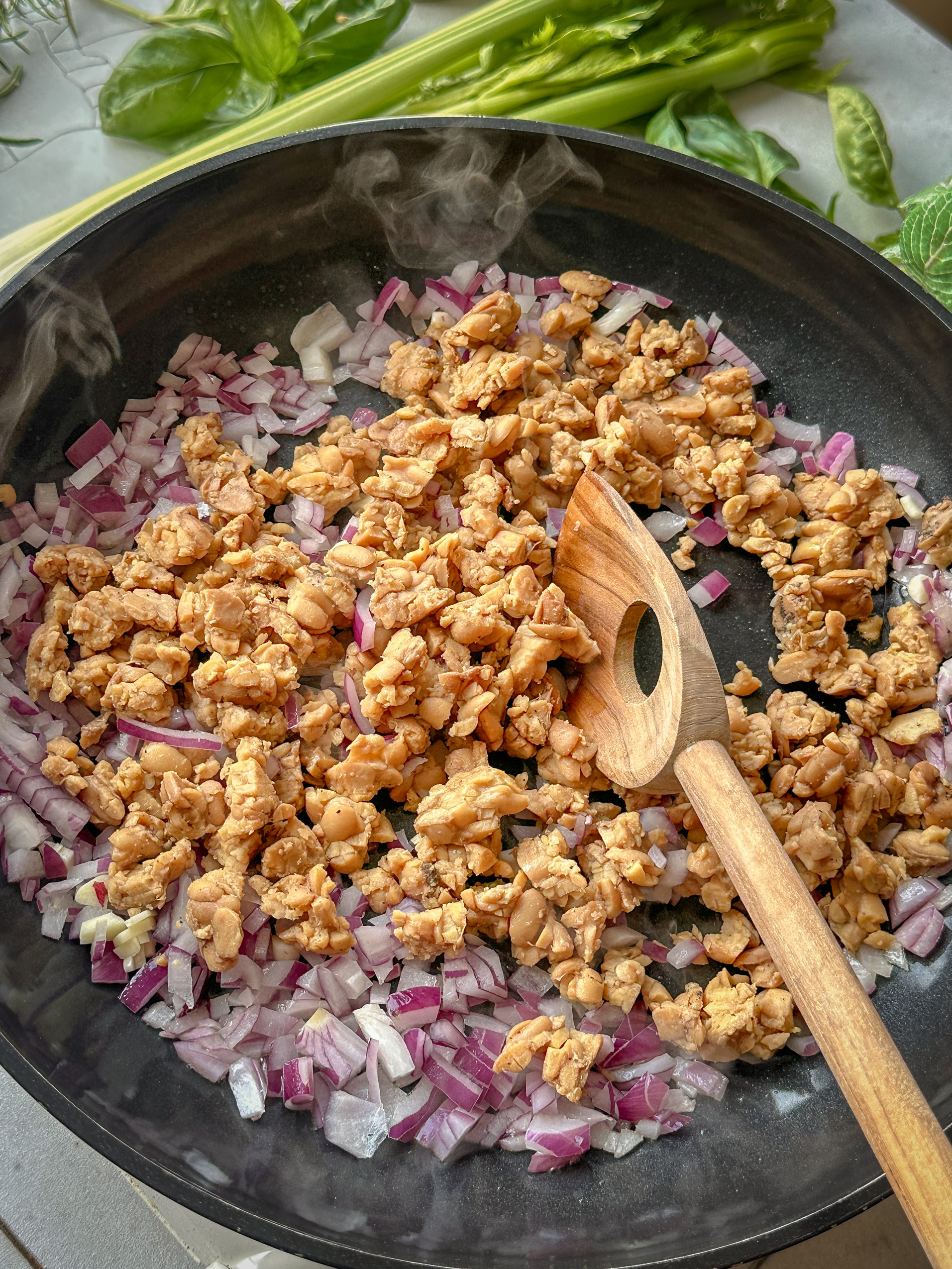 Mit Zwiebeln angebratener Tempeh in einer Pfanne