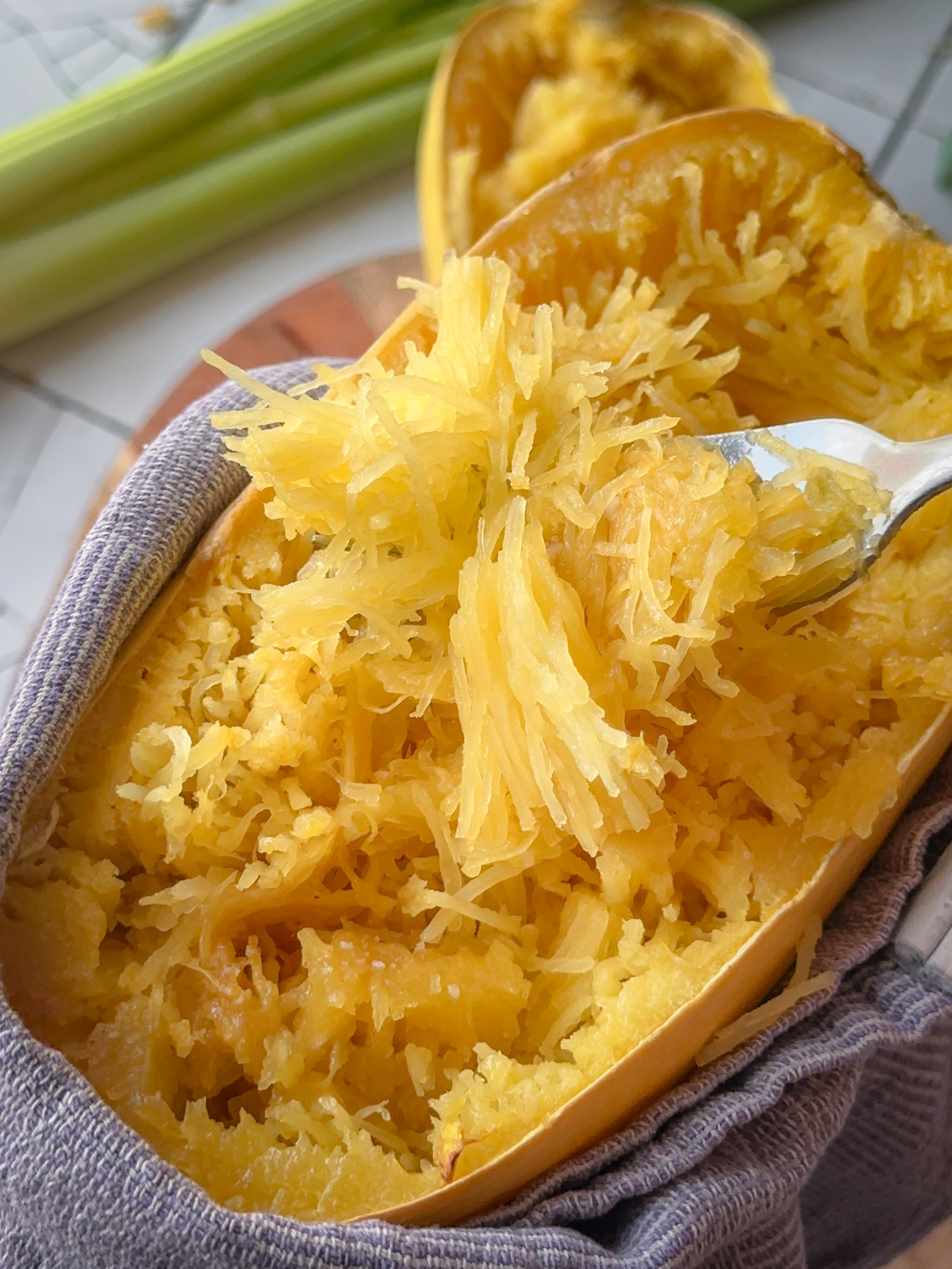 Eine Gabel zieh das Fruchtfleisch eines Spaghettikürbisses in Fäden